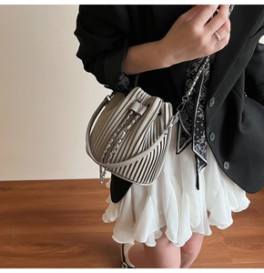 Detail of grey pleated bucket bag with leather handle and metal chain shoulder strap