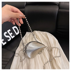 Macro shot of silver shell-shaped clutch with bead chain and metallic stripe texture