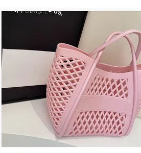 Détail du sac à main rose ajouré avec motif à losanges et poignées intégrées souples