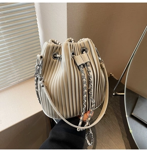 Detail of grey pleated bucket bag with metallic chain strap and drawstring closure