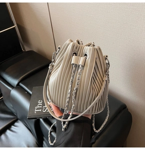 Detail of grey bucket bag showing vertical pleats and silver metal chain drawstring
