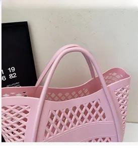 Détail du sac de plage en plastique rose ajouré avec des doubles poignées durables
