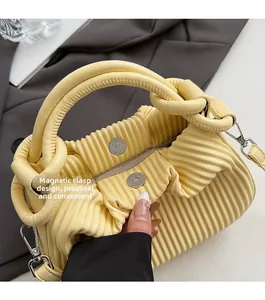 Detail of yellow pleated handbag showing magnetic closure and premium inner lining