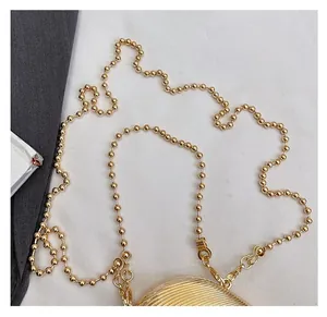 Detail of the golden shell-shaped acrylic evening bag with a round spherical chain strap