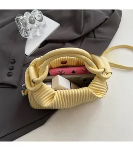 Detail view of the spacious inner compartment of this yellow pleated handbag