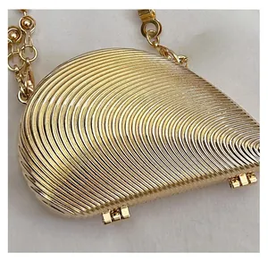 Detail of shell-shaped metallic evening bag featuring radial textures and gold hardware
