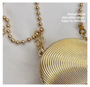 Detail of detachable gold ball chain strap on luxury metal evening bag with screw thread finish