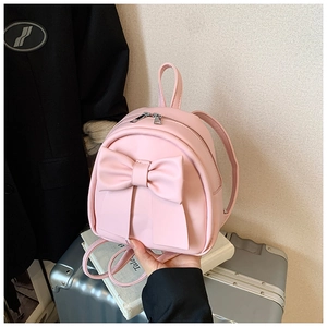 Pink mini backpack detail featuring a large bow design held in hand for scale