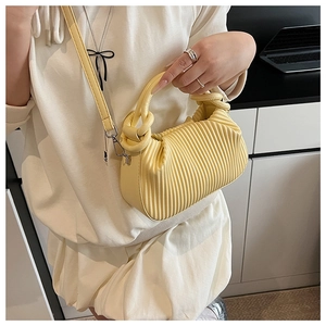 Model wearing a light yellow pleated handbag with vertical ruffles and thin shoulder strap