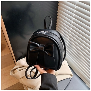 Detail of a black mini PU leather backpack featuring a large decorative bow and dual zippers