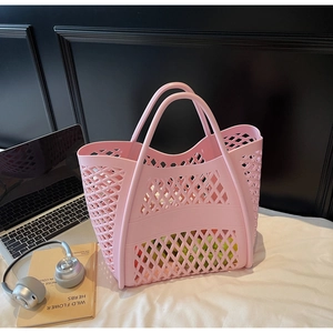 Sac panier rose ajouré avec motif en losange contenant des raisins sur un bureau