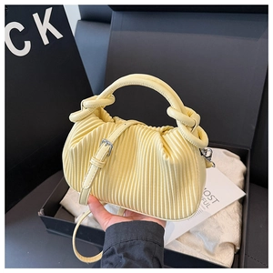 Detailed view of pale yellow pleated tote bag with vertical accordion texture and silver hardware