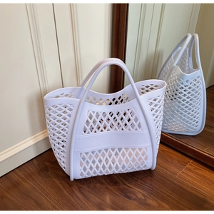 Détail du sac cabas tressé blanc ajouré avec bande large sur sol en bois