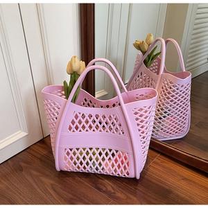 Détail du sac fourre-tout tissé ajouré rose avec motif en maille sur sol en bois