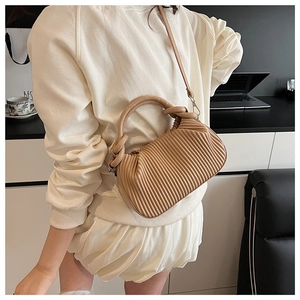 Close-up of pleated khaki crossbody bag showing detailed texture and strap design