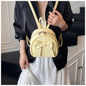 Detail of light yellow bow backpack featuring double zippers and slender adjustable straps