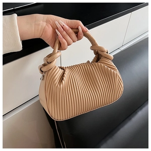 Detail of light brown pleated handbag with knotted handle and elegant faux leather texture