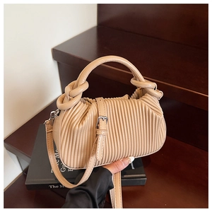 Detail of beige pleated handbag with knot handle on dark wooden stairs background
