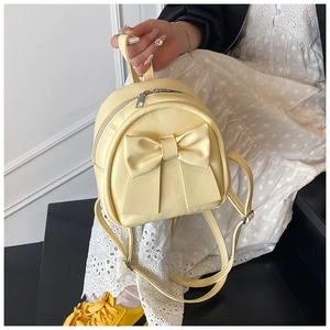 Close-up of stylish light yellow mini backpack with a large bow detail and metal zipper