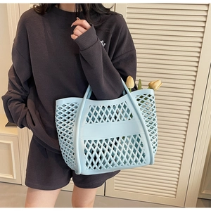Détail du sac fourre-tout évidé bleu clair avec fleurs dans un décor naturel