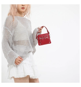 Fashionable red rivet mini handbag with silver studs shown on a casual female model