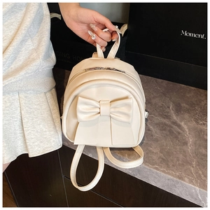 Detail of cream mini backpack featuring a large bow and adjustable shoulder straps
