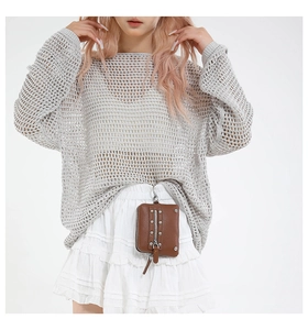 Detail of a grey hollow-out knit sweater paired with a white tiered ruffle mini skirt