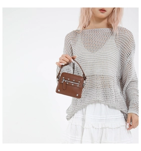 Detail of brown lychee leather mini bag with silver metal rivets and functional zipper pocket