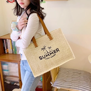 Woven straw tote bag with palm tree embroidery and brown leather handles for summer travel