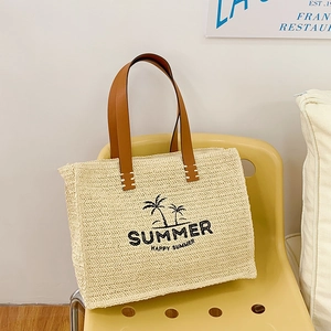 Handwoven straw tote bag with leather handles and summer graphic for vacation use