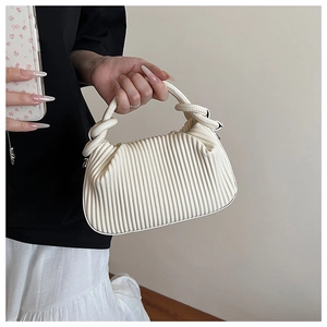 Close-up of cream pleated handbag featuring unique knotted handle and vertical texture