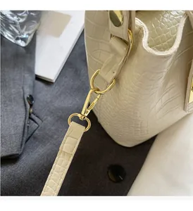 Detailed view of high-gloss gold hardware on cream crocodile pattern bucket bag