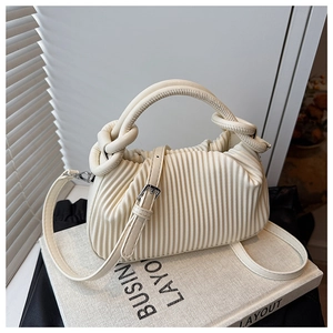 Detailed view of cream pleated handbag featuring vertical texture and silver hardware