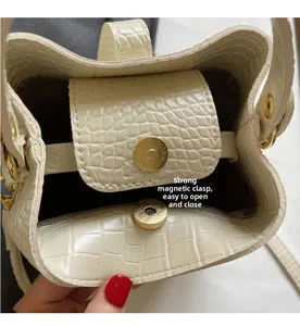 Detail view of cream crocodile pattern bag featuring a strong golden magnetic buckle closure