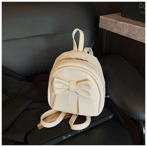 Detail view of cream PU leather backpack with a large bow and silver metal zippers