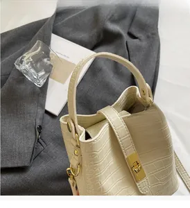 Close-up of beige crocodile pattern leather bucket bag with gold hardware and top handle