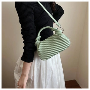 Detailed close-up of vertical pleated texture and knotted handle on mint green handbag