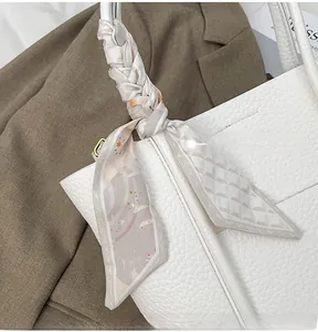 Close-up of white pebble leather tote bag with a floral silk scarf tied on the handle