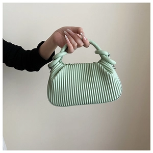 Detail of mint green handbag featuring vertical pleats and a unique knotted handle design