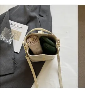 Internal view of beige crocodile embossed bucket bag with folding umbrella and two phones