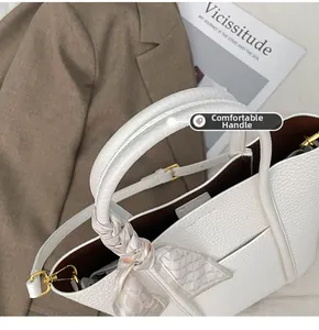 Detail of white litchi pattern leather tote bag handle with silk scarf decoration