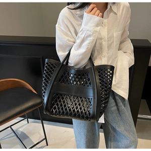 Détail d'un grand sac fourre-tout noir ajouré avec maille géométrique sur une chaise en bois