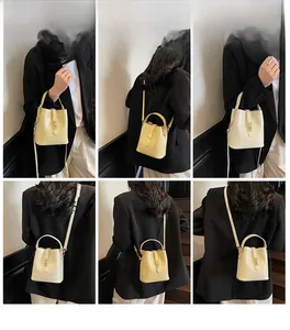 Detail view of cream yellow crocodile embossed bucket bag with gold metal clasp