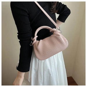 Close-up of light pink pleated handbag with vertical accordion folds and knot handle