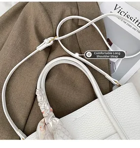 Detail of white lychee leather tote bag with adjustable strap and decorative silk scarf