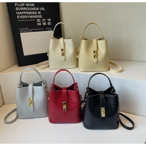 Detailed display of five colors of crocodile texture bucket bags on a white tiered stand
