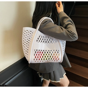 Gros plan d'un sac cabas tressé blanc ajouré montrant sa grande capacité et texture