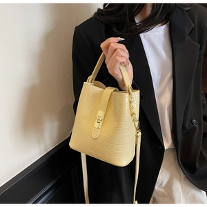 Detail of yellow crocodile embossed bucket bag with gold lock and adjustable strap