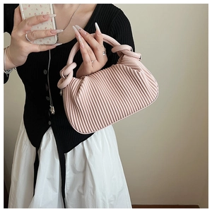 Pink pleated mini handbag with knotted handle detail shown in a lifestyle setting
