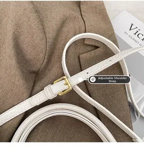 Detail of adjustable white lychee leather shoulder strap with golden metal buckle